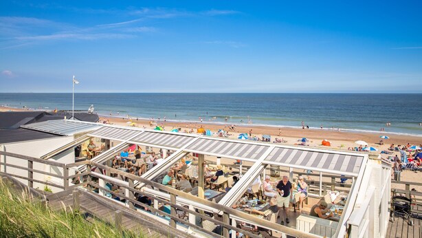 A beachside restaurant with outdoor seating overlooking the ocean.