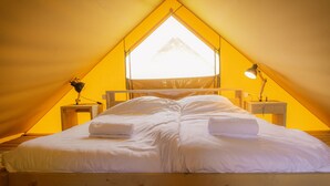A single bed in a tent with a triangular window, two bedside lamps, and a wooden floor. - Well Furnished Tent Lodge with Terrace near Veluwe (Voorthuizen)
