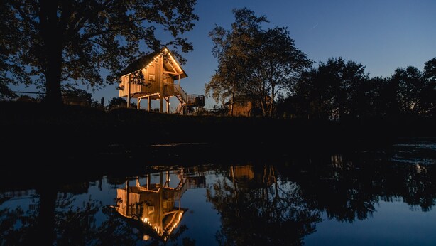 Een huis met balkon en spiegelbeeld in het water.