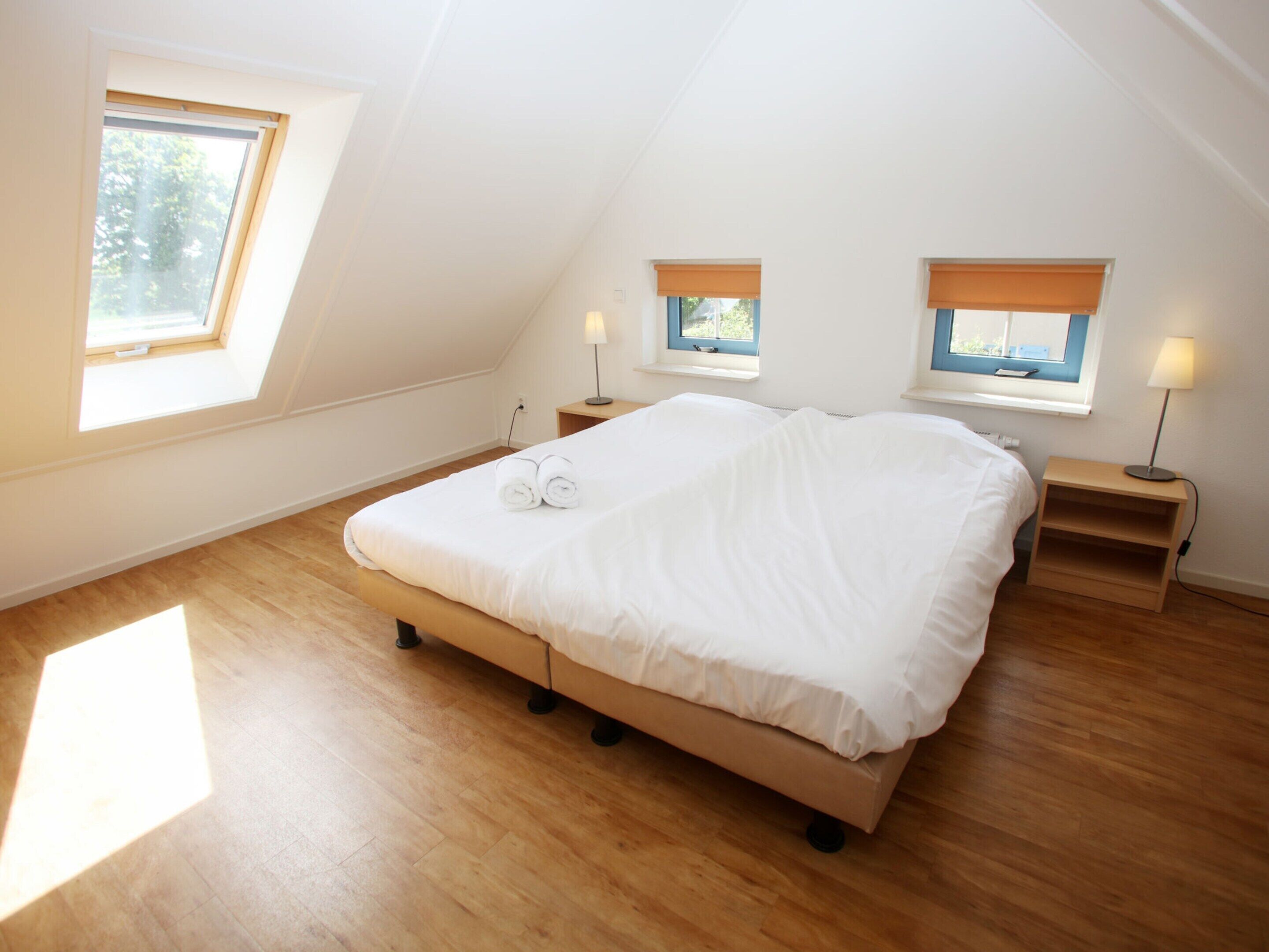 A bedroom with a large bed, two bedside tables, and a skylight.