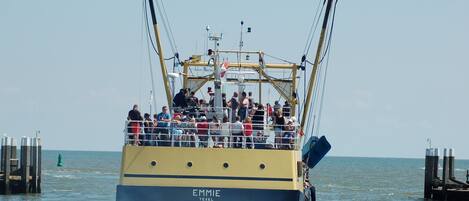 A boat named EMMIE TEXEL with passengers on deck, moving through water.