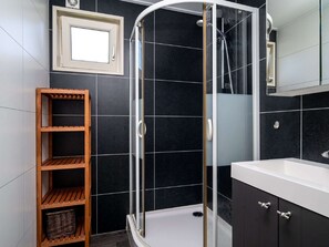 Ein modernes Badezimmer mit einer gläsernen Duschkabine, einer Holzeinrichtungsanlage und einem großen Spiegel über dem Waschbecken.