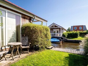Ein Haus mit einer Holzterrasse, einem kleinen Boot und einem Rasen.