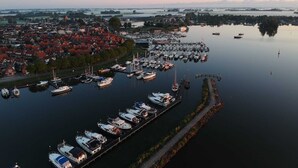 A marina with boats docked and a town in the background. - Cozy Chalet Right on the Water in Friesland (Akkrum)