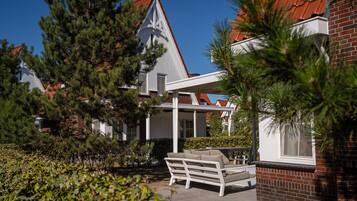 A residential property with a brick exterior, white window frames, and a red-tiled roof.