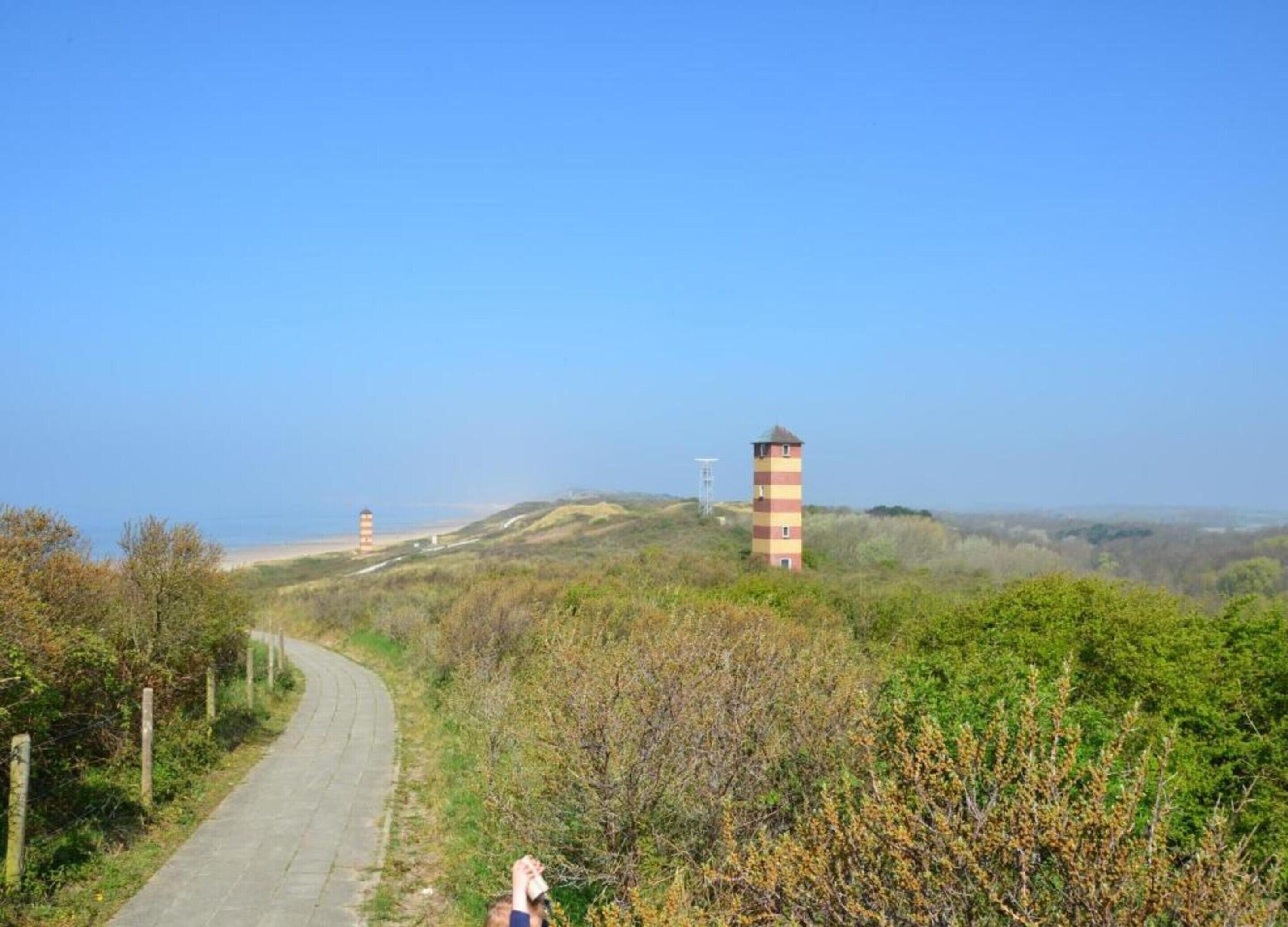 A coastal road with a lighthouse and a tower in the distance.
