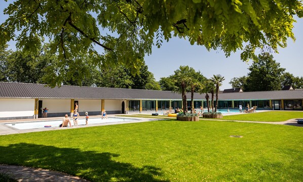 A poolside area with a covered seating area, a swimming pool, and a building with a tiled roof. - Beautiful House With Garden (Hellendoorn)