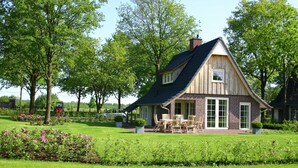 A house with a sloped roof, brick exterior, and a patio with outdoor furniture. - Beautiful House With Garden (Hellendoorn)