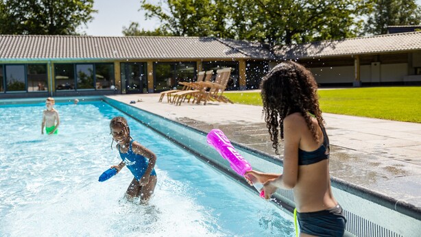 A swimming pool with people playing and splashing water. - Beautiful House With Garden (Hellendoorn)