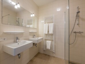 Een moderne badkamer met twee wastafels, een douche en een handdoekrek.