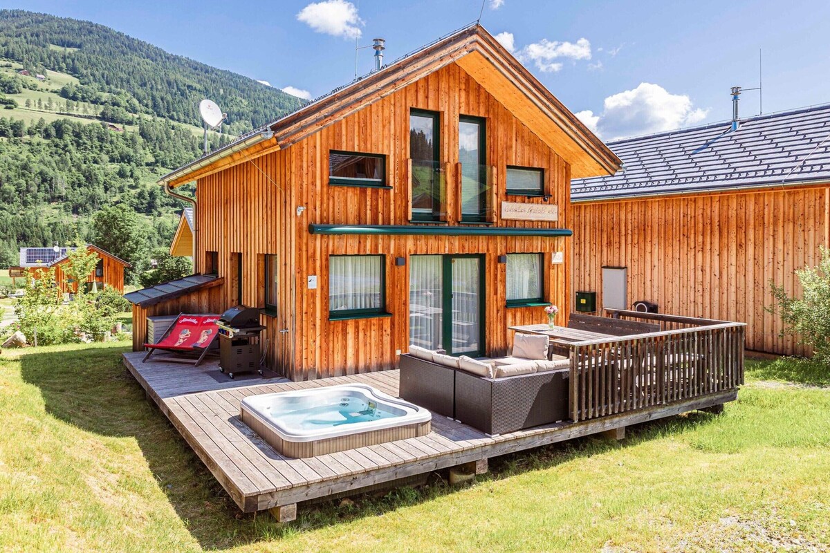 Una baita di legno con vasca idromassaggio, area salotto esterna e terrazza.