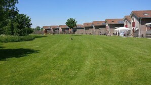 Camp de gespa amb un parc infantil i una fila d'edificis amb teulades vermelles i panells solars.