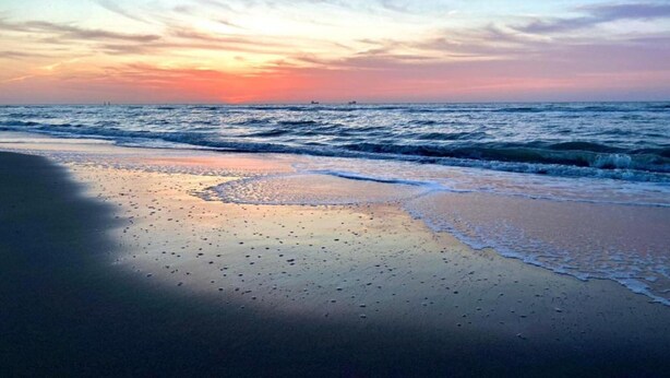 Une plage avec des vagues et un coucher de soleil.