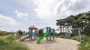 A playground with a green slide and a small shelter. - Ameland Lodge w/ Veranda (Hollum)