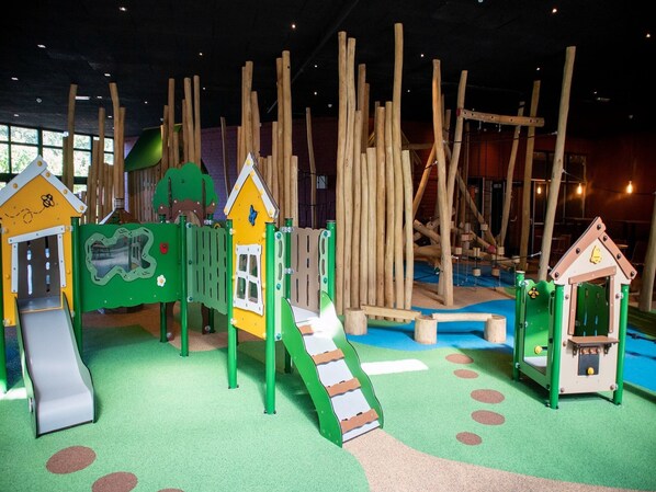 Un espace de jeux pour enfants avec différentes structures, notamment un toboggan et des jeux d’escalade.