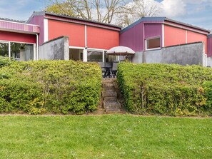 A modern building with a red facade, a covered outdoor seating area, and a well-maintained garden. - Well-kept Bungalow With Microwave Near Valkenburg (Walem)