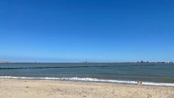 A sandy beach with calm waters and a clear blue sky.