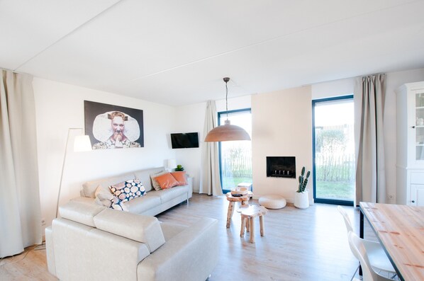 A modern living room with a sofa, a coffee table, and a dining table. - Villa Oesterdam Wellness 6 People (Tholen)