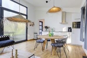 Eine moderne Küche mit weißen Schränken, einem runden Holztisch und schwarzen Stühlen.