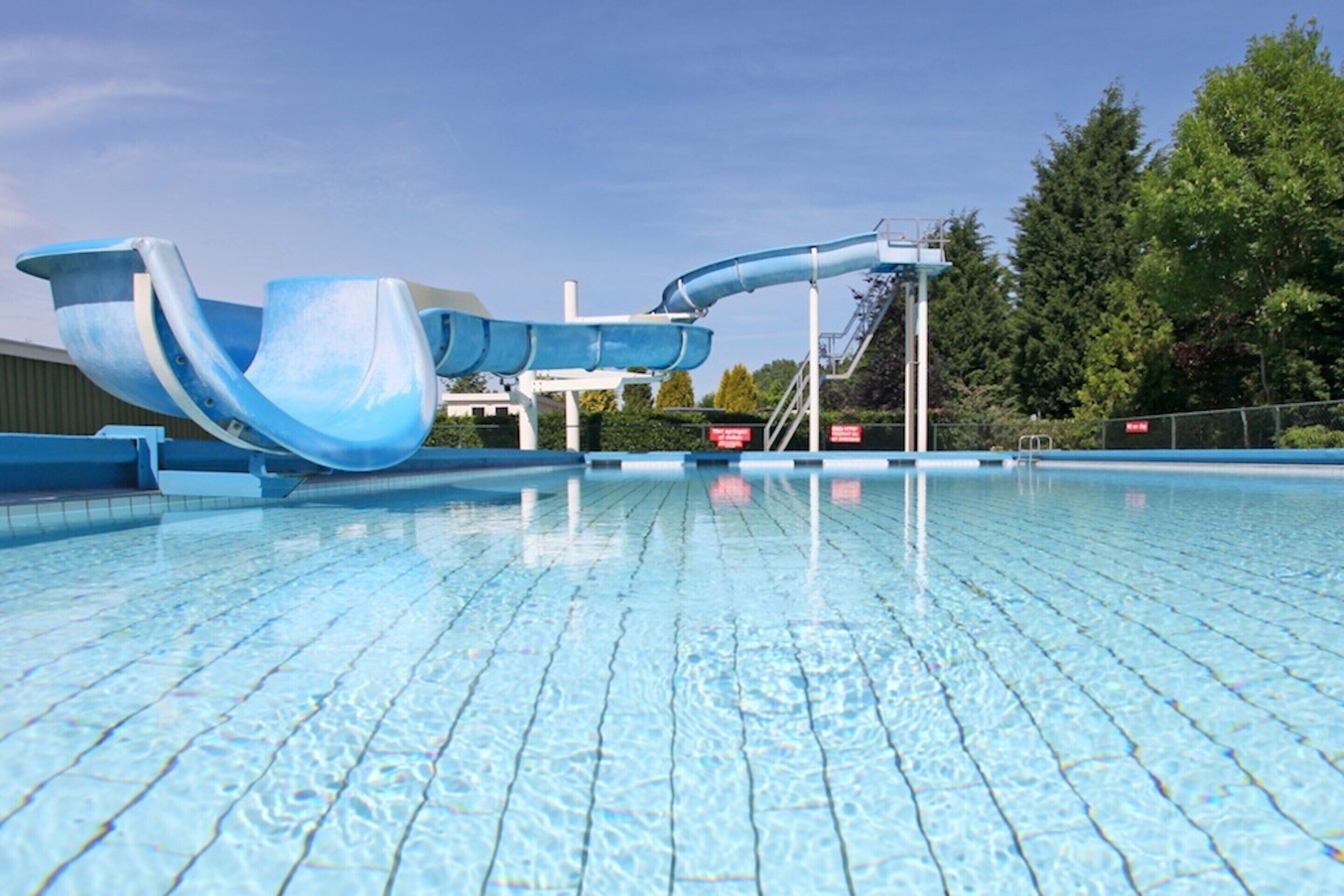 A swimming pool with a blue water slide and a clear blue sky.