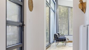 A modern room with large windows, a chair with cushions, and a radiator. - Getaway With Covered Veranda (Enter)