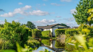 A house with a pond in front, surrounded by greenery. - Comfortable Chalet With Dishwasher, Near the Sea in Egmond (Egmond aan den Hoef)
