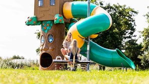 A playground with a slide and a treehouse structure. - Comfortable Chalet With Dishwasher, Near the Sea in Egmond (Egmond aan den Hoef)