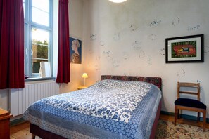A bedroom with a bed, a chair, a window with curtains, a lamp, and wall decorations. - Holiday Home in Steffenshagen With Terrace (Steffenshagen)