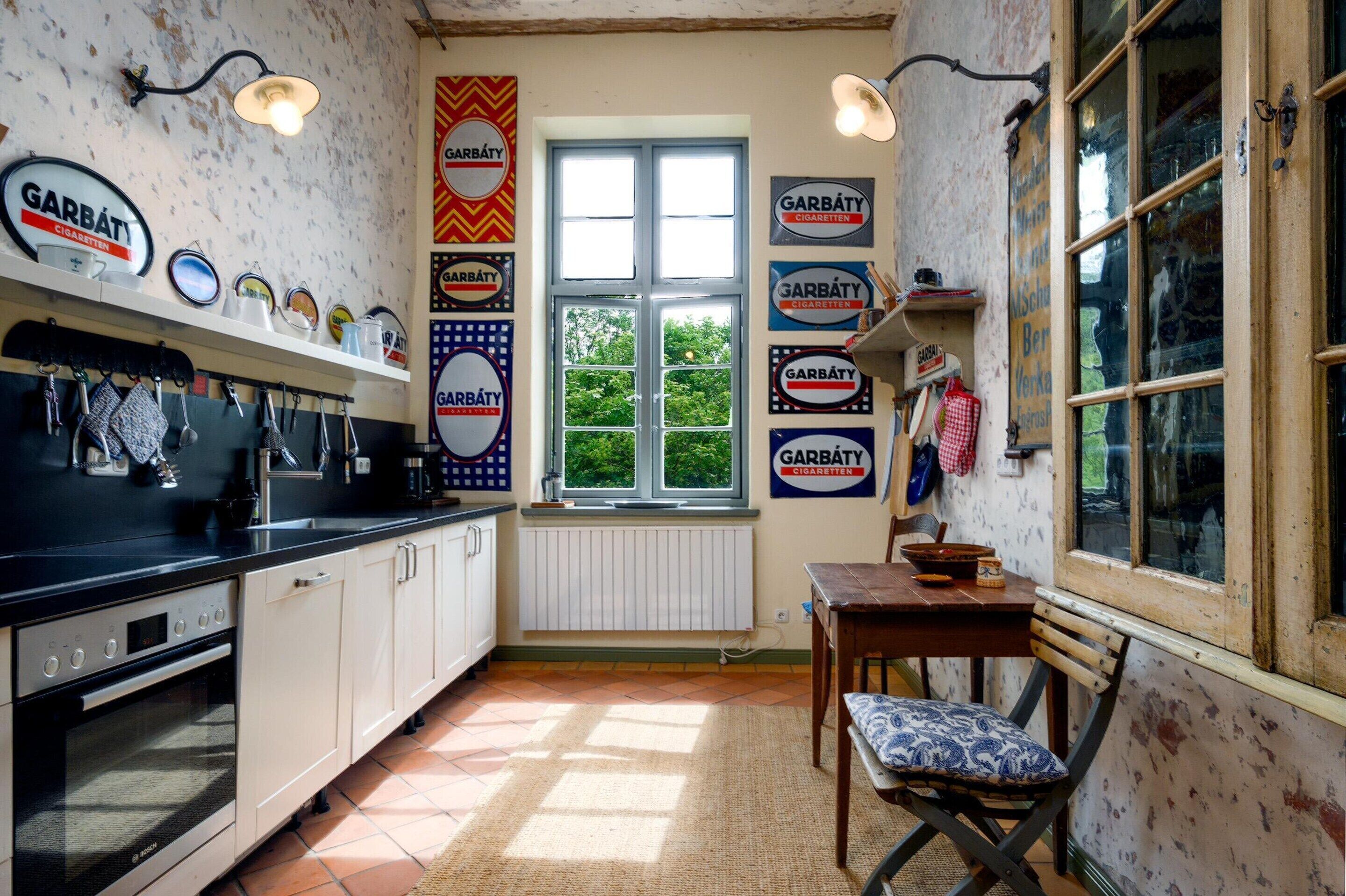 A kitchen with a Bosch oven, a window with a view of greenery, and multiple signs reading 'Garbáty Cigarettes'.