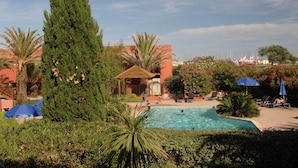 A pool area with lounge chairs, a gazebo, and a view of the sea. - Apartment in France Near Serene Beaches (Agde)