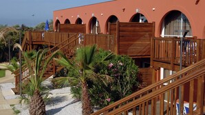 A building with wooden balconies, a palm tree, and a staircase leading to an upper level. - Apartment in France Near Serene Beaches (Agde)