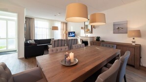 Una camera d'albergo moderna con un tavolo da pranzo in legno, un divano e una TV.