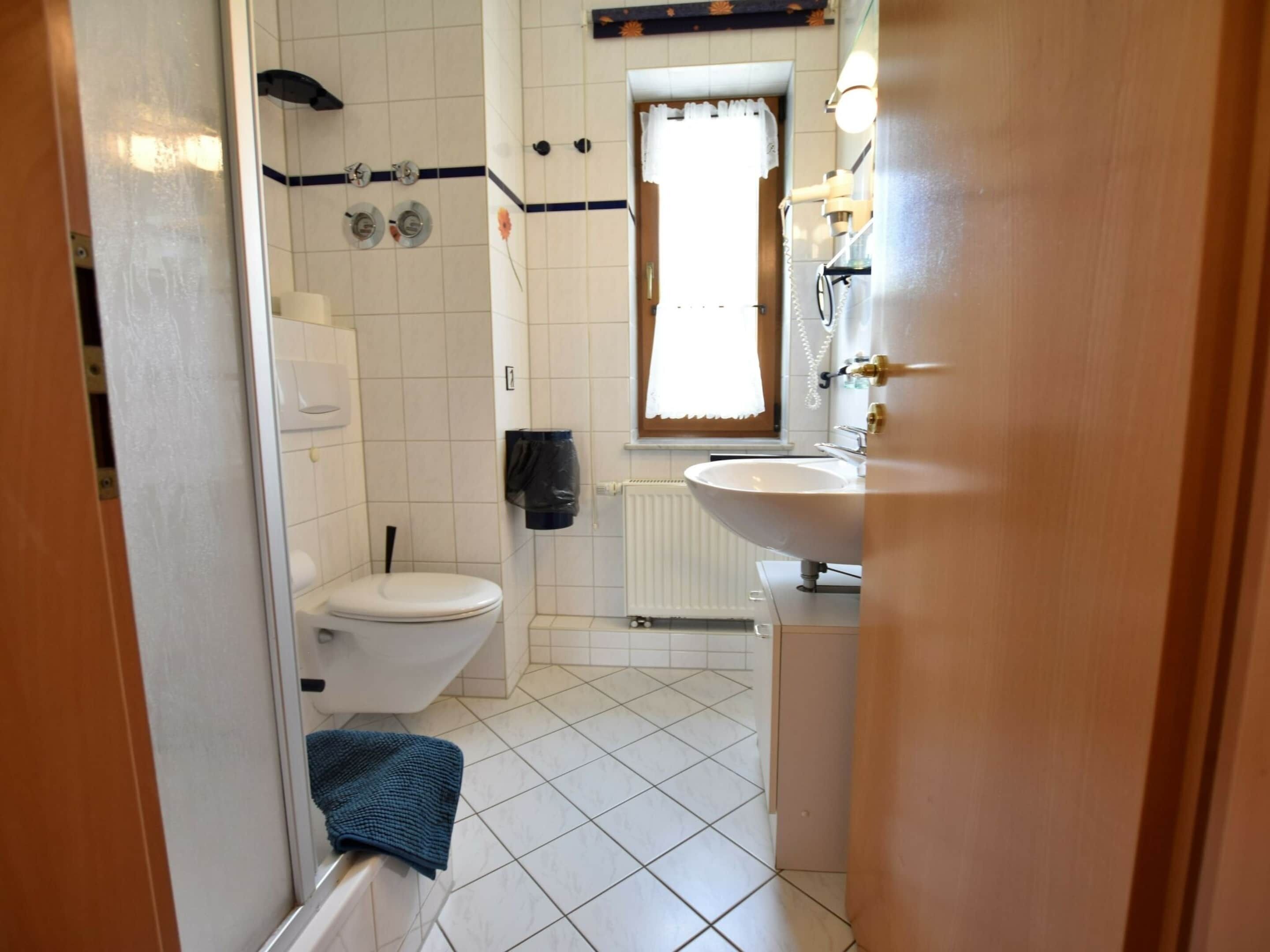 A small bathroom with a toilet, sink, and shower.