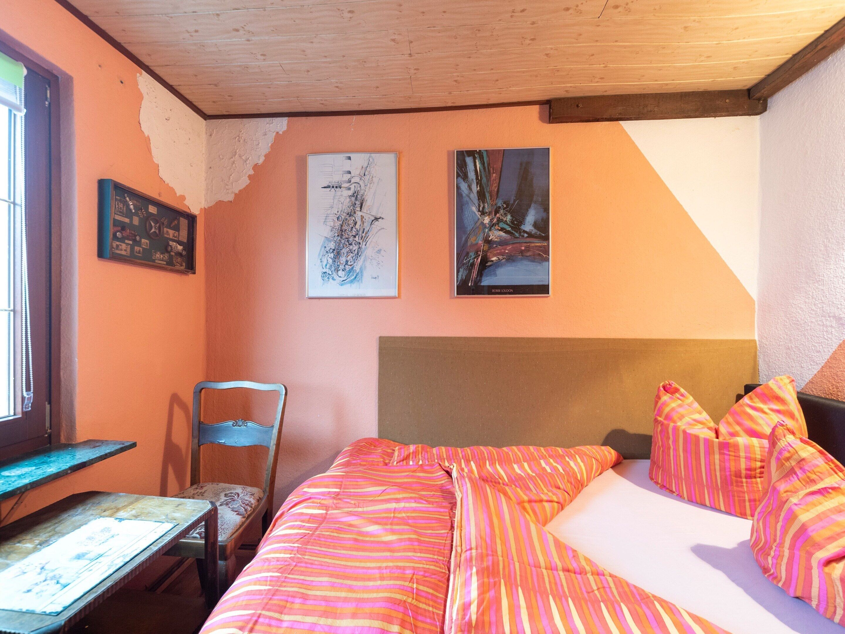 Une chambre à coucher avec un lit, une chaise et deux tableaux accrochés au mur.