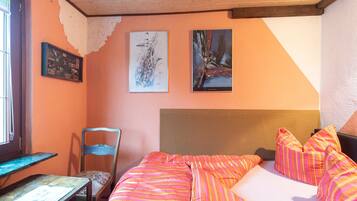 Une chambre à coucher avec un lit, une chaise et deux tableaux accrochés au mur.