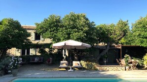 A poolside area with a clear blue pool, lounge chairs, and an umbrella. - Provence Charm With Pool (Viens)