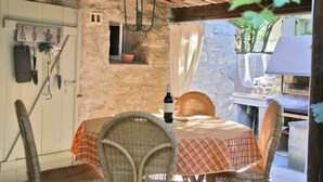 An outdoor dining area with wicker chairs and a table covered with a checkered tablecloth. A bottle of wine and a glass are on the table. - Provence Charm With Pool (Viens)