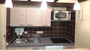 A kitchen with wooden cabinets, a microwave, a sink, and pendant lights. - Ferienhaus im Hochsauerland mit Terrasse (Bestwig)