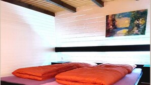 A bedroom with a bed, a brick wall, and a painting. - Ferienhaus im Hochsauerland mit Terrasse (Bestwig)