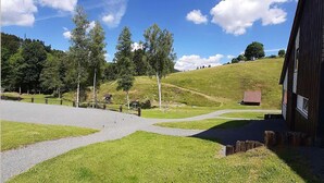 A grassy area with a paved path leading to a wooden building. - Ferienhaus im Hochsauerland mit Terrasse (Bestwig)