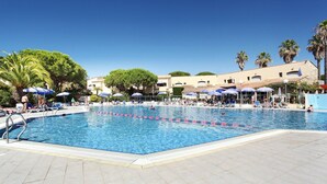 A swimming pool with blue water, surrounded by lounge chairs and umbrellas. - Peaceful Stay Among Pines (Agde)