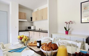 A breakfast table with croissants, fruit, and juice, a microwave, and a potted plant in a hotel room. - Spacious Apt Near the Beach (Fréjus)