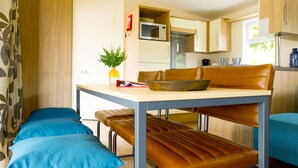 A compact kitchen with a dining area, featuring a table, bench seating, and a microwave.