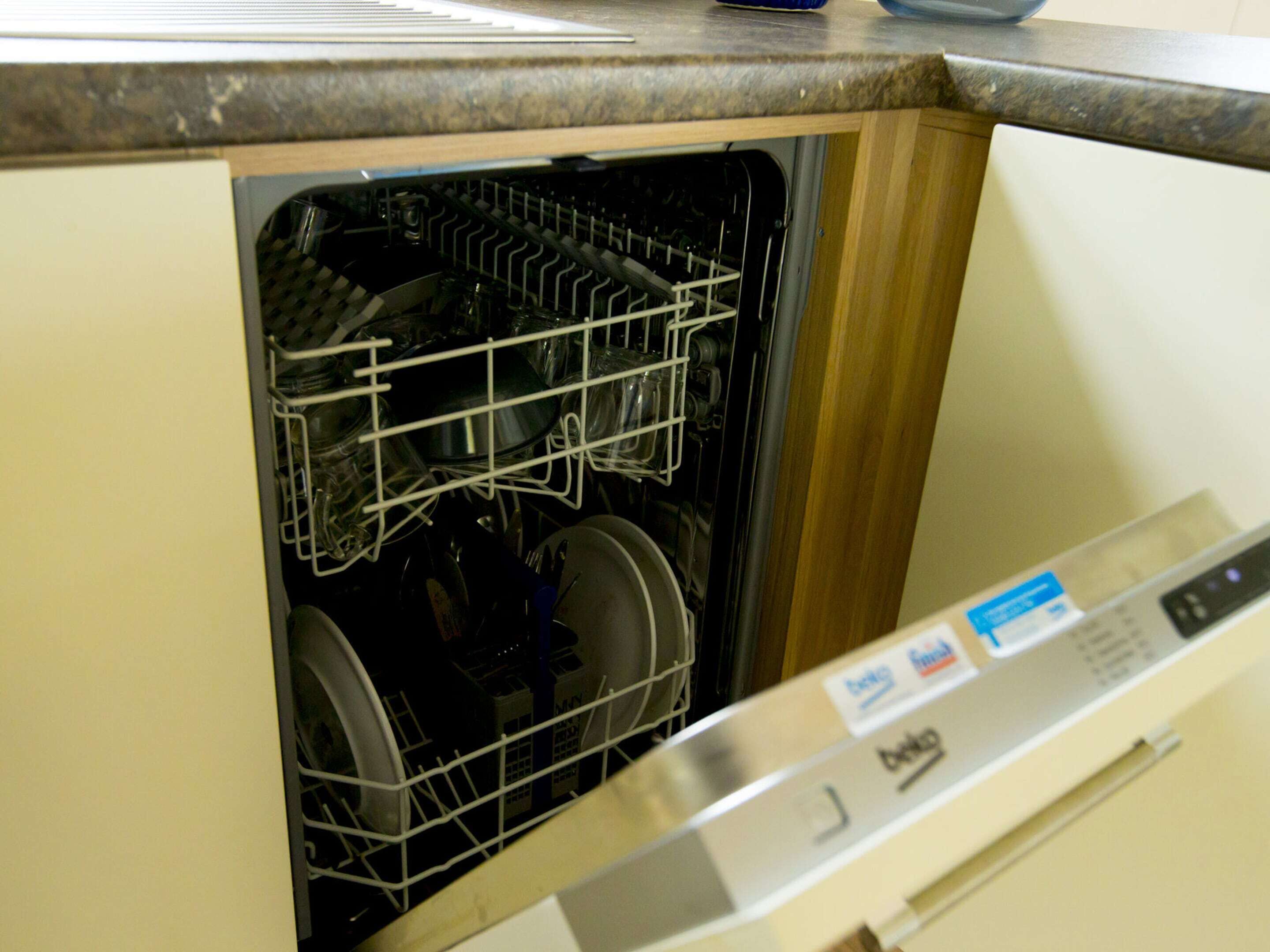 A dishwasher with a control panel and a metal rack inside.