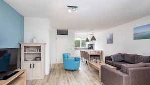 Una sala de estar moderna con televisor, sofá y comedor.