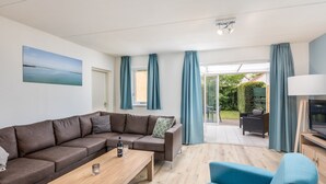 Una sala de estar moderna con un sofá de cuero marrón, una mesa de centro de madera, un sillón azul y un mueble para televisor.