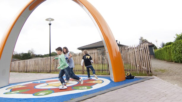 Un parque infantil con una zona de juegos colorida y una valla de madera al fondo.