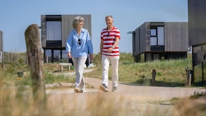 Two people walking on a path in a modern outdoor setting with contemporary buildings in the background. - Special, Compound Group Accommodation, Near the Sea (Zandvoort)