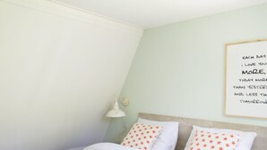 A bedroom with a bed, two pillows with star patterns, a bedside lamp, and a wall with a framed quote. - Forest-edge Family Bungalow (Hoenderloo)