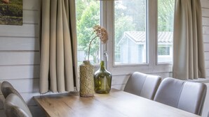 Un comedor con una mesa de madera, dos sillas, un jarrón y una botella.